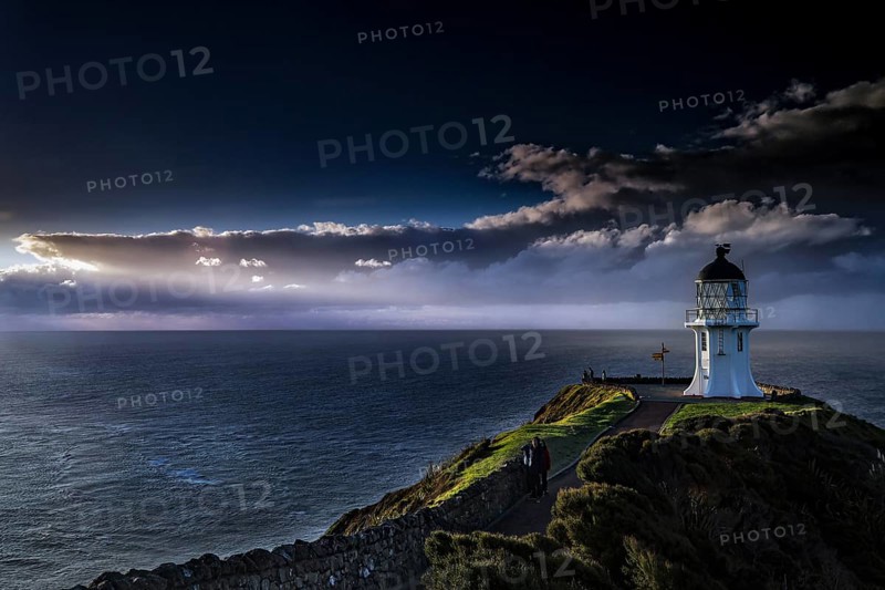 Lighthouse under a dramatic sky lights up the sea at Cape Reinga, Cape Reinga, Northland, New Zealand
