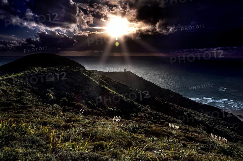 Darkness and sun rays at Cape Reinga with the lighthouse in the foreground, Cape Reinga, Northland, New Zealand
