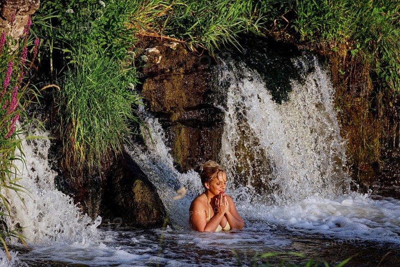 A woman enjoys water under Ventas Rumba waterfall in Kuldiga, Kuldiga, Latvia