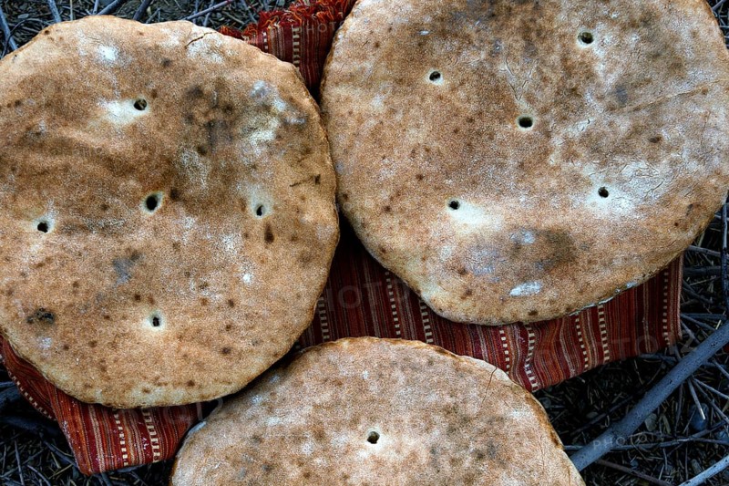 Three large flatbread loaves on a support in the desert, Beni Tajite, Morocco