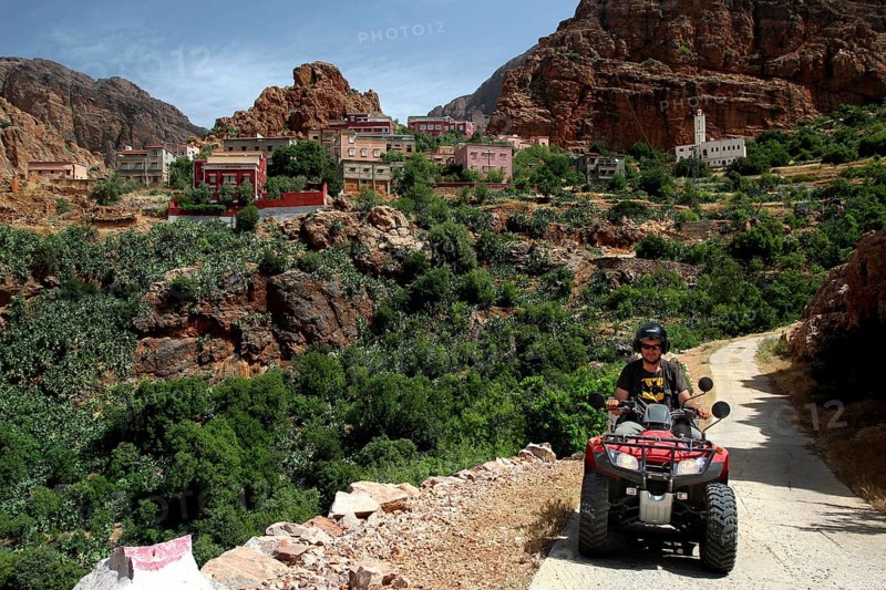 Quad driver on a trail through a mountainous village and green surroundings, Anergui, zero, Morocco