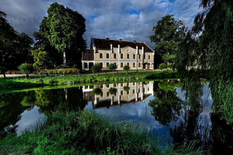 Kuldiga District Court with reflection in a quiet pond and surrounded by trees, Kuldiga, Courland, Latvia