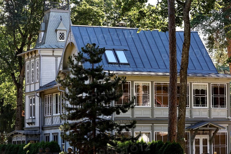 Elegant art nouveau wooden house with eye-catching blue roof under tall trees, Majori, Jurmala, Latvia