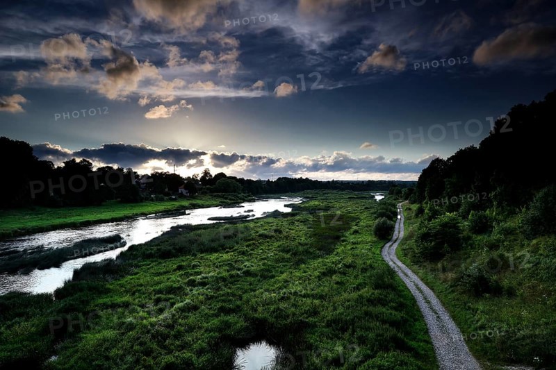 The Windau valley in Kuldiga with lush vegetation and dramatic sky, Kuldiga, Windau, Latvia