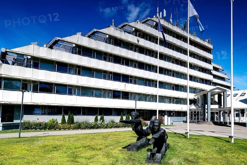 Modern sanatorium building with flags and well-kept green area against blue sky, Vaivari, Jurmala, Latvia