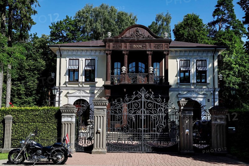 Large wooden house with ornate gate and parked motorcycle in front of it, Jurmala, Latvia