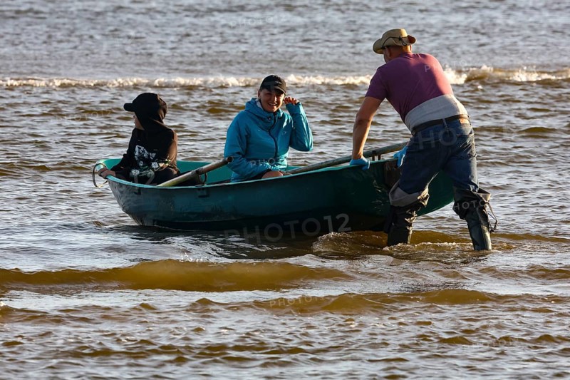 Three people in a small rowing boat on Kolka beach, Kolka, Latvia