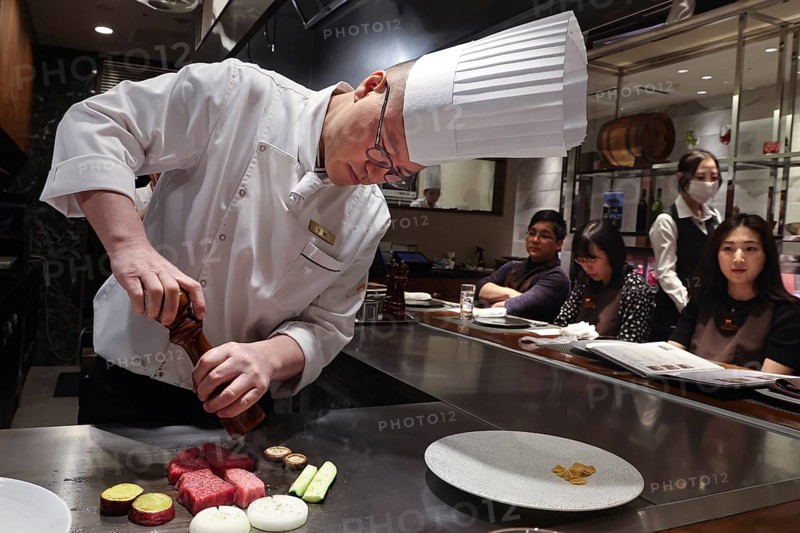 Chef prepares Kobe steak and guests watch in amazement at the Kobe Plaisir restaurant, Kobe, Hyogo, Japan