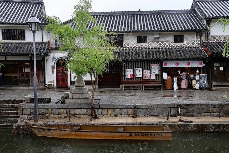 Traditional buildings along a canal in Kurashiki with a small boat in the foreground, Kurashiki, Okayama, Japan