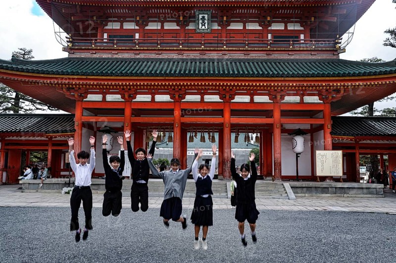 Group of students jump in front of a large torii in Kyoto, Kyoto, Okazaki, Japan