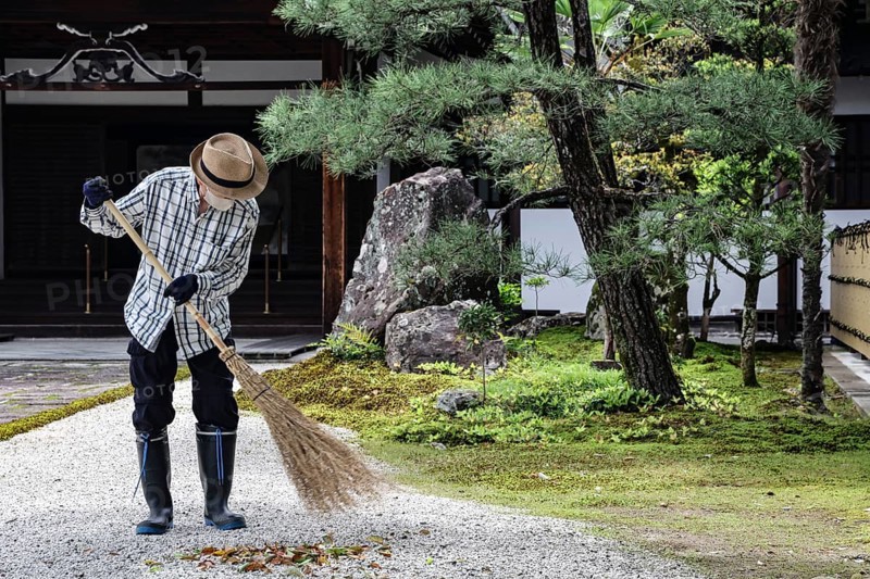 A gardener cultivates the garden with a broom in a traditional setting, Kyoto, Okazaki, Japan
