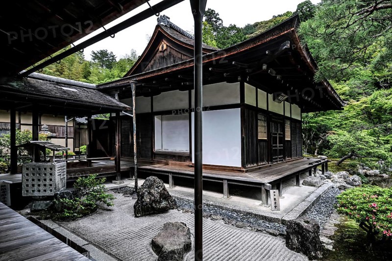Zen garden with traditional pavilion surrounded by carefully arranged rocks and green vegetation, Kyoto, Japan