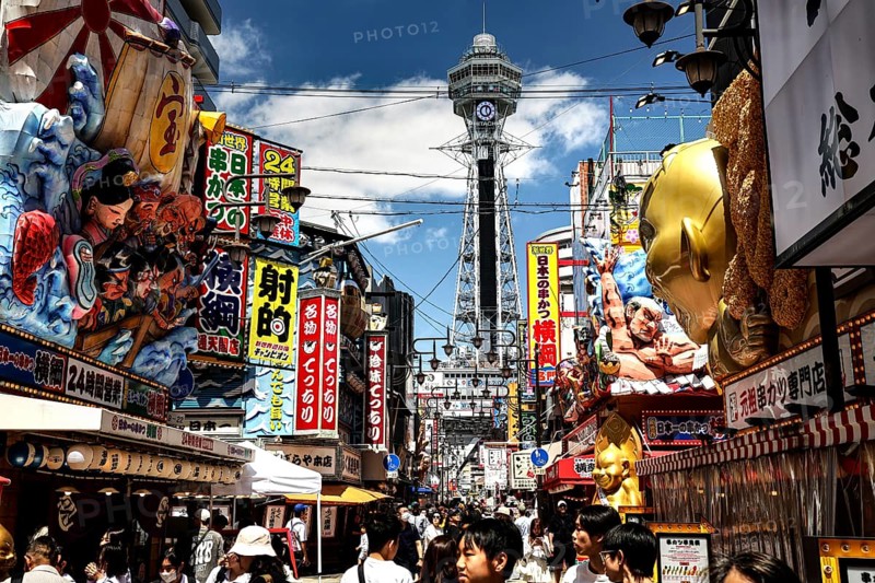 Bustling street in Shinesekai with the Tsutenkaku Tower in the background, Osaka, Japan