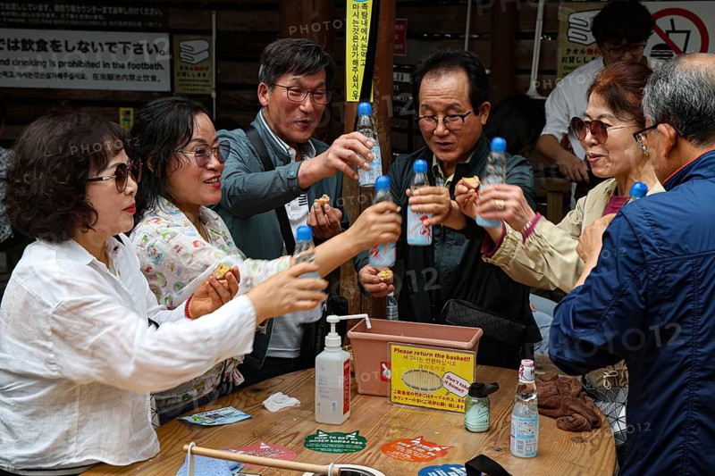 Friends at Kamado Jigoku in Beppu toast with bottles and enjoy the atmosphere, Beppu, Oita, Japan