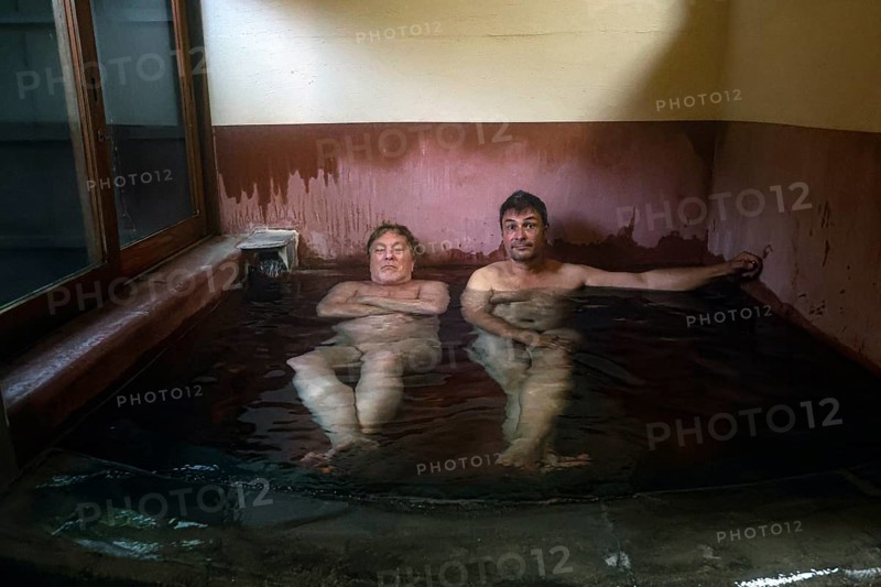 Two men relax in a traditional onsen at Ryokan Asogen