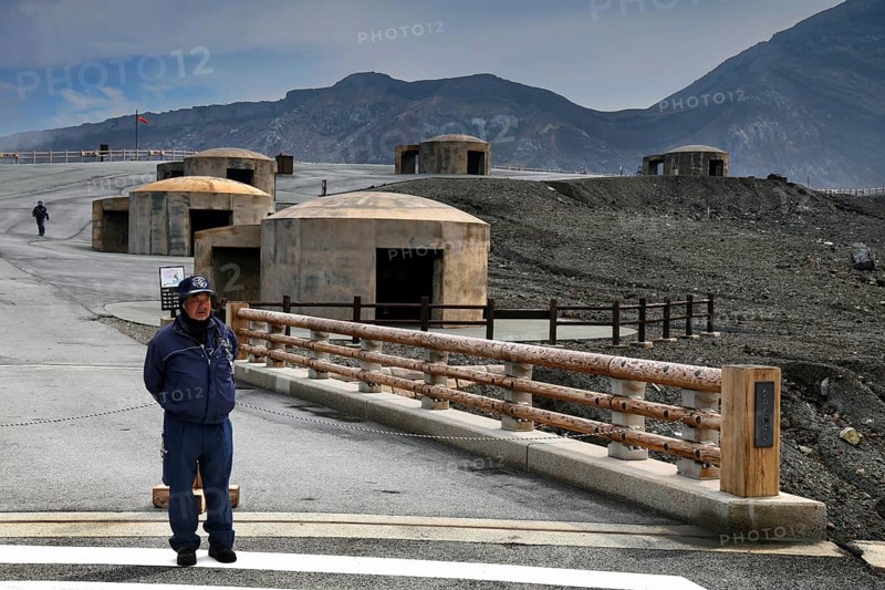 A bunker and rangers stand in the dramatic volcanic landscape of Nakadake, Aso, Aso, Kyushu, Japan