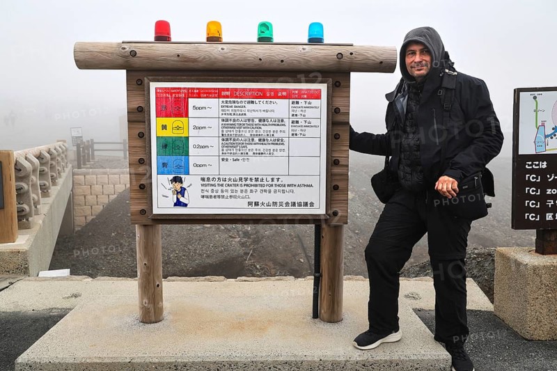 Person standing next to a warning sign in the fog of Nakadake Crater, Aso, Kumamoto, Japan