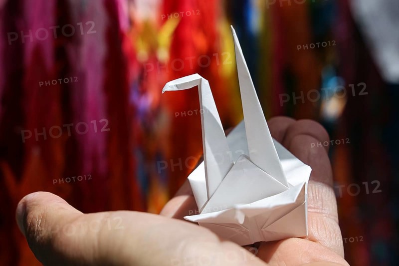 An origami crane is held by one hand in Hiroshima Peace Park, Hiroshima, Japan