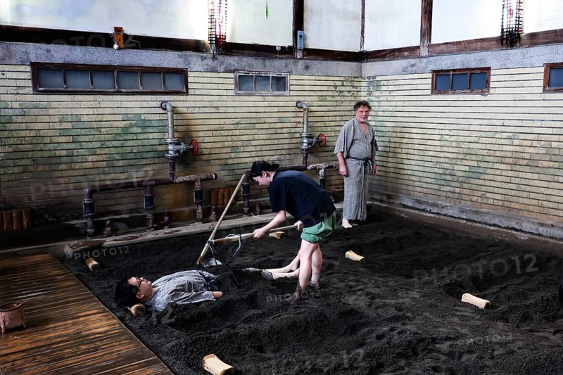 A sand bath at Takegawara Onsen Beppu, one person being cared for by another, Beppu, Oita, Japan