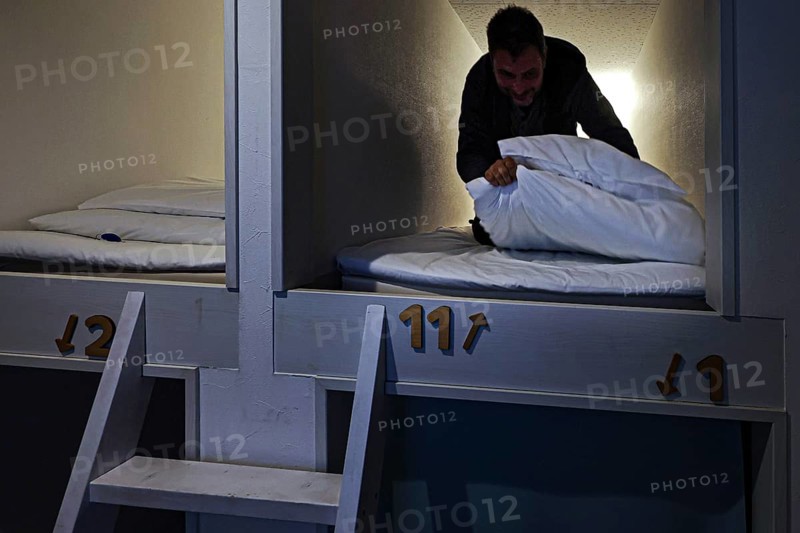 Man in sleeping capsule in a Japanese capsule hotel. Cozy and compact accommodation, Ise, Mie, Japan