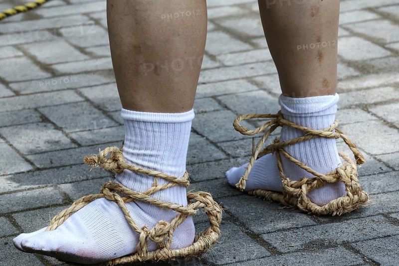 Legs in traditional straw shoes on cobblestones, Nikko, Japan