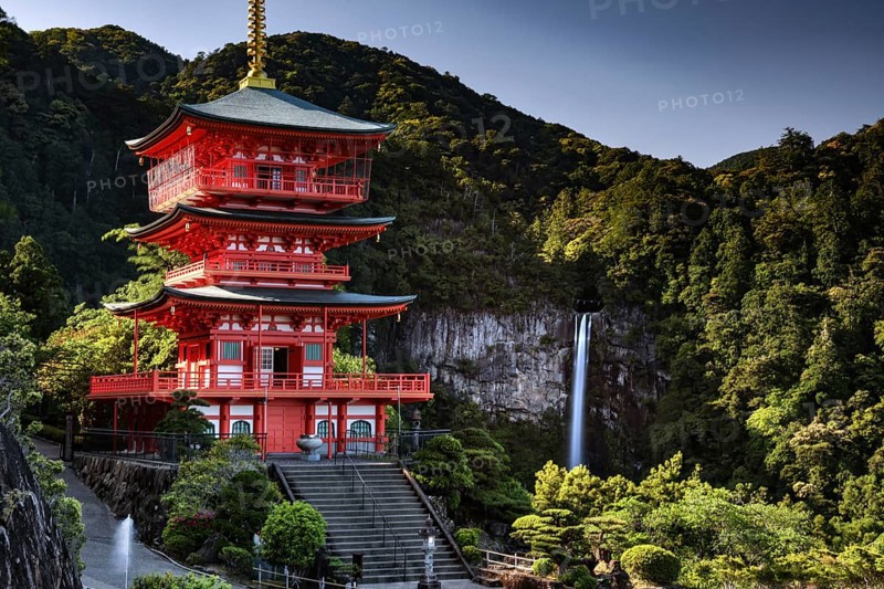 Red pagoda in front of Nachi Waterfall in the green forest of Seiganto-ji, Nachi, Wakayama, Japan
