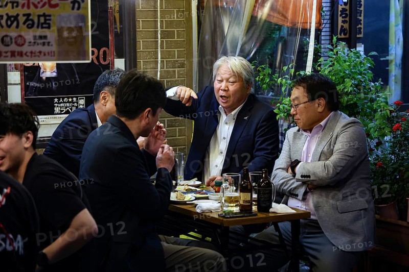 Men in suits talk vividly at a table in the Hoppy-dori, Tokyo, Tokyo, Japan