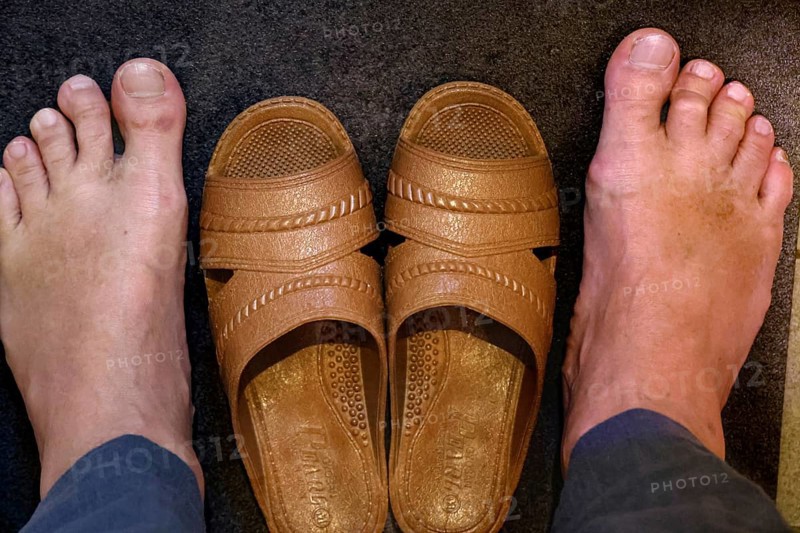 Two feet next to a pair of brown toilet shoes on dark ground, Osaka, zero, Japan