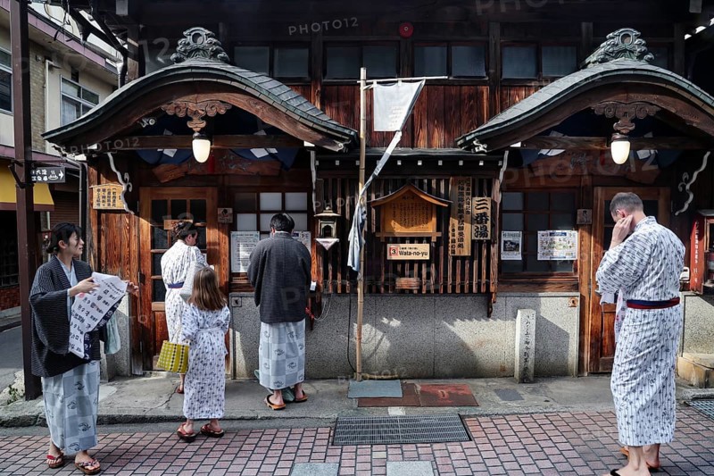 People in yukata in front of a traditional public bath, Yamanouchi, Japan