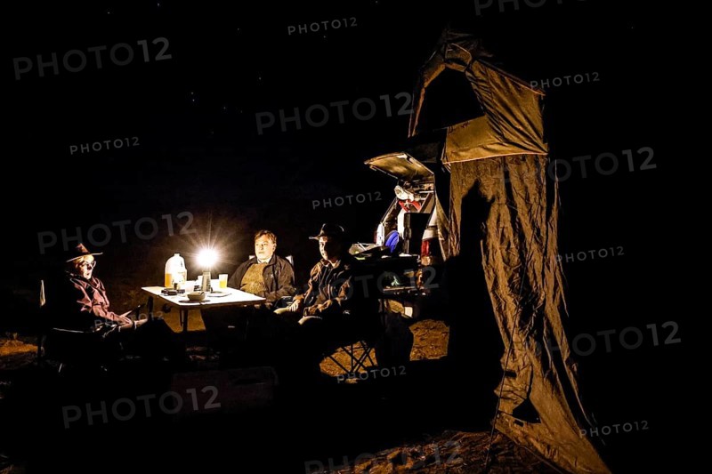 Camp at night with lights, people, vehicle in desert environment, Oodnadatta Track, Australia