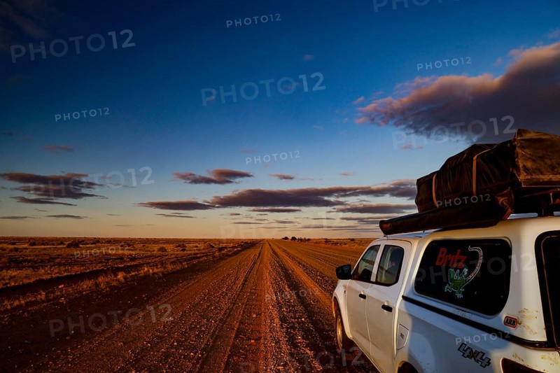 Vehicle on rural road under dramatic evening sky in outback, Oodnadatta Track, null, Australia