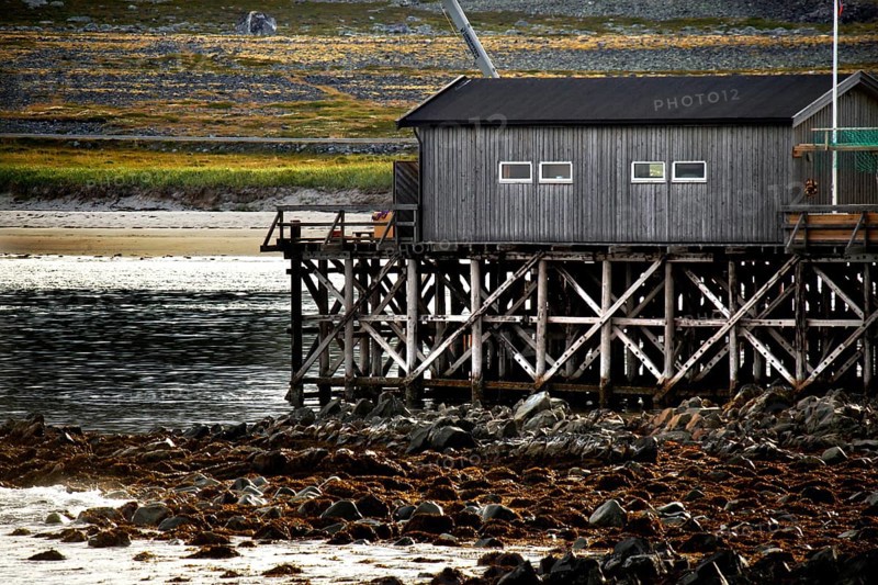 Wooden buildings on piles near the water in the Hamningberg coast
