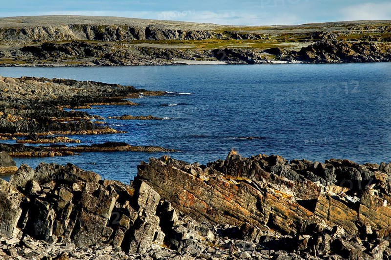 Rough coastline with rocks and sea under blue sky, N Hamningberg, zero