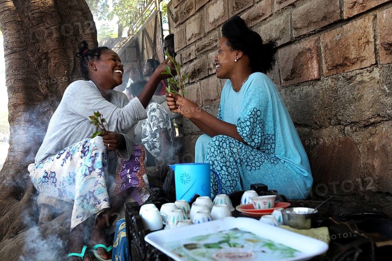 Two woman enjoy a traditional coffee ceremony and share moments of laughter, Asbe Teleri, Afar, Ethiopia