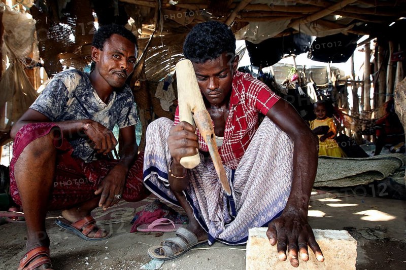 Muhammad's brothers work on a salt block in the hut, Ahmedela, Tigray, Ethiopia