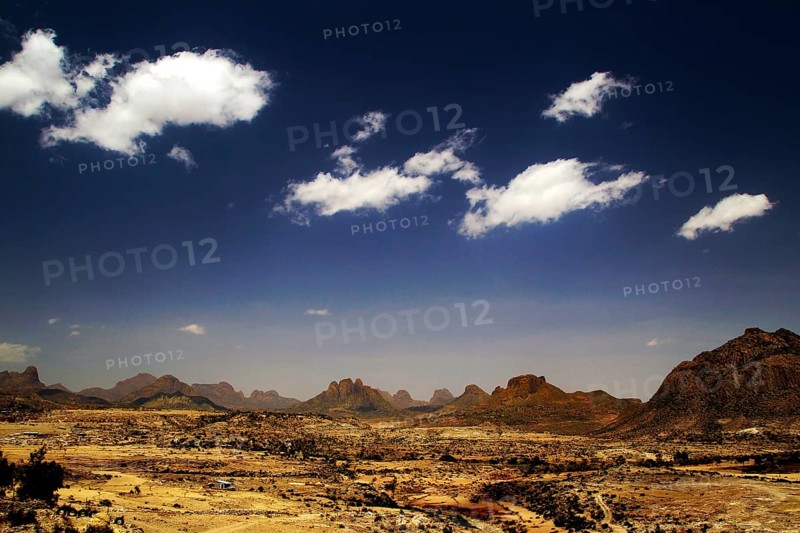 Wide desert landscape with distinctive mountains and isolated clouds in a clear sky, Adua, Tigray, Ethiopia