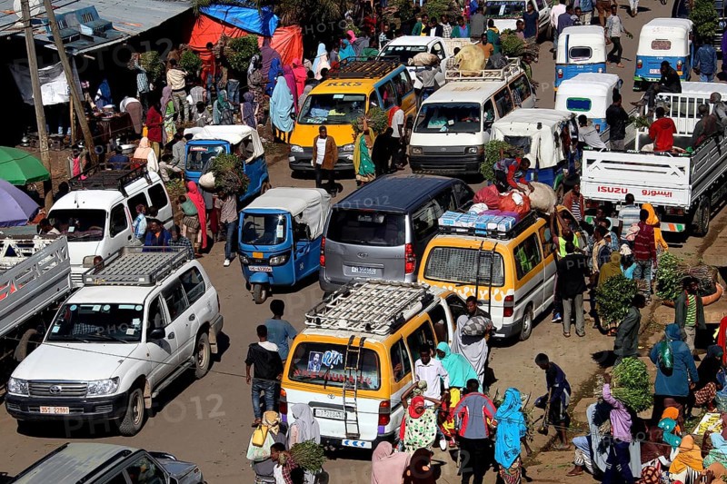 Lively street scene in Awaday with lots of cars and people wearing colorful clothes, Awaday, Ethiopia