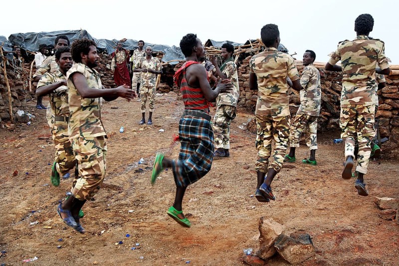 Soldiers dance in their military uniforms on rocky ground at Erta Ale Camp, Erta Ale, Ethiopia