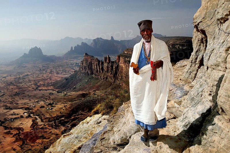 Abba Tesfay stands in traditional clothing in the impressive Gheralta Mountains, Gheralta Mountains, Ethiopia