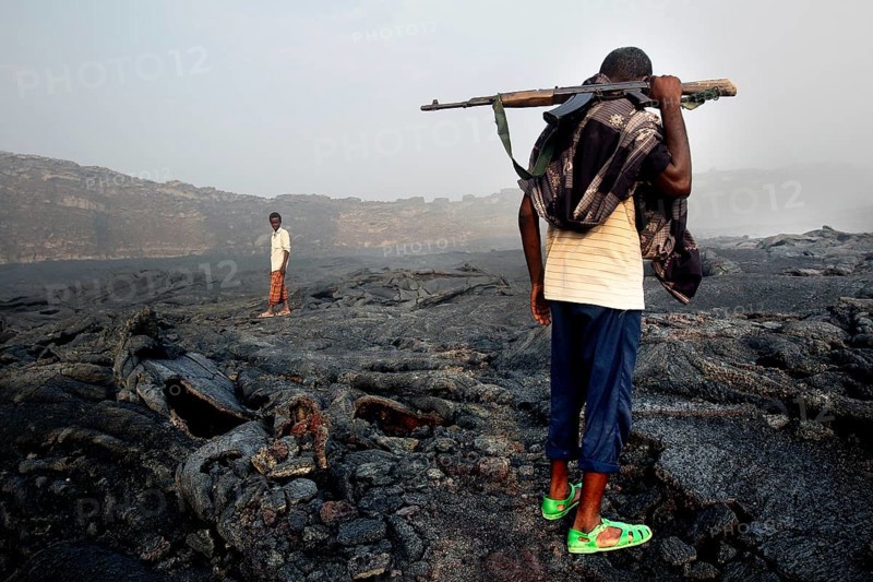 Members of the escort crew cross the volcanic terrain of Erta Ale, Erta Ale, Afar, Ethiopia