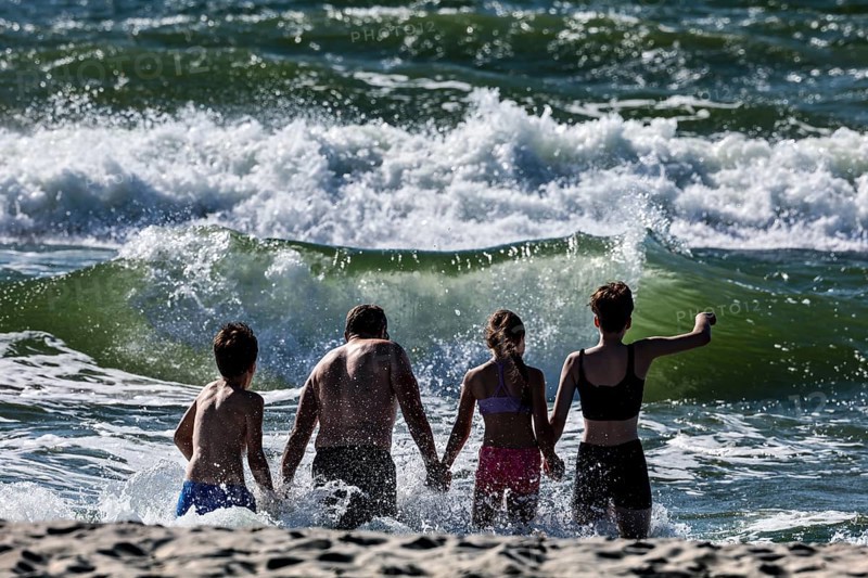 Bathers enjoy the wild waves on a sunny beach in Nida, Nida, Curonian Spit, Lithuania