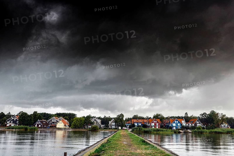 Pier leads to a village under a dramatic sky in Pervalka, Pervalka, Lithuania