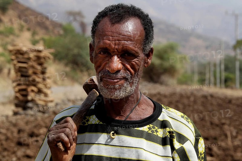 Portrait of a farmer in the Semien Mountains with ethnic clothing and tools