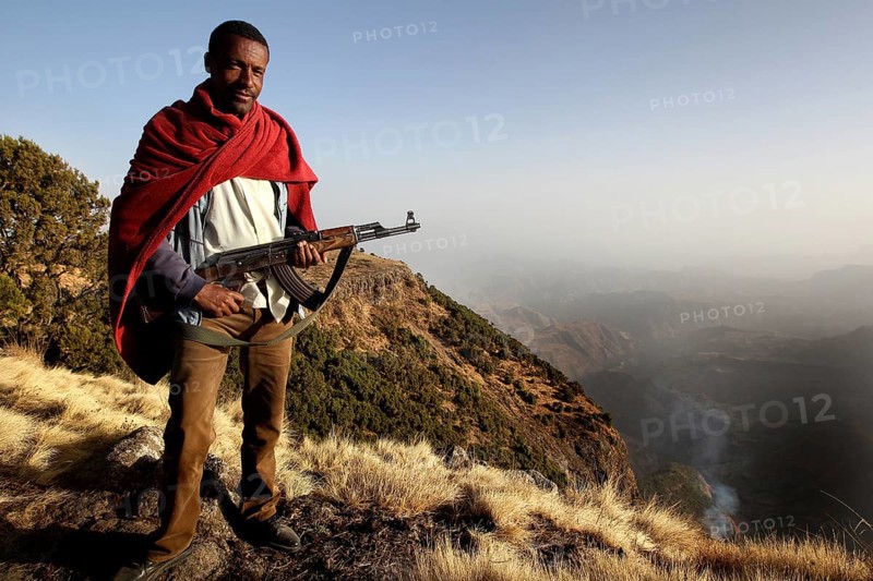 Armed companion stands in front of a vast mountain panorama in Semien Mountain National Park, Semien Mountain National Park, Ethiopia
