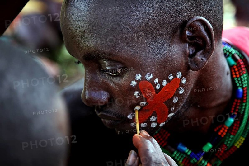 A hamer receives elaborate red and white face painting as part of an initiation ritual, Turmi, null, Ethiopia