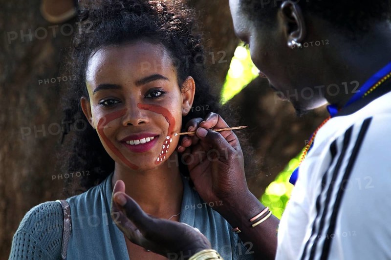 Tourist receives face painting from a hammer during an initiation ritual, outdoor cultural exchange, Turmi, null, Ethiopia