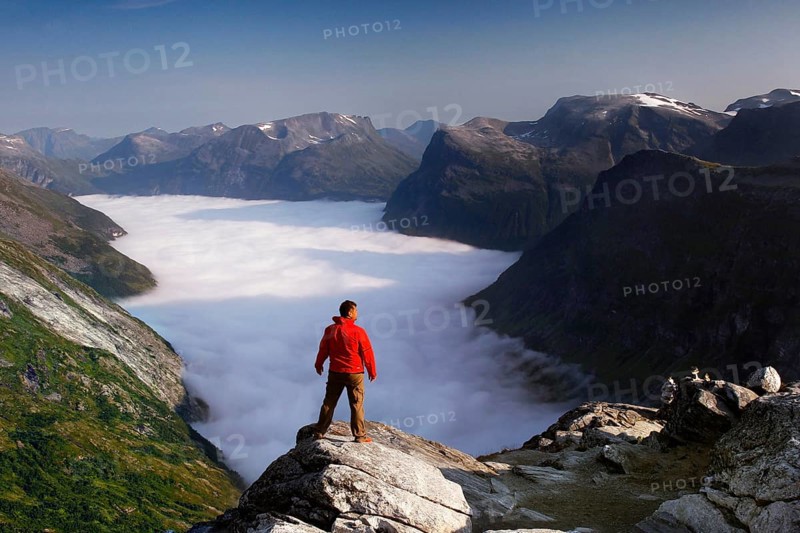 View from Dalsnibba of the Geiranger Fjord with a sea of clouds, enjoyed by a hiker
