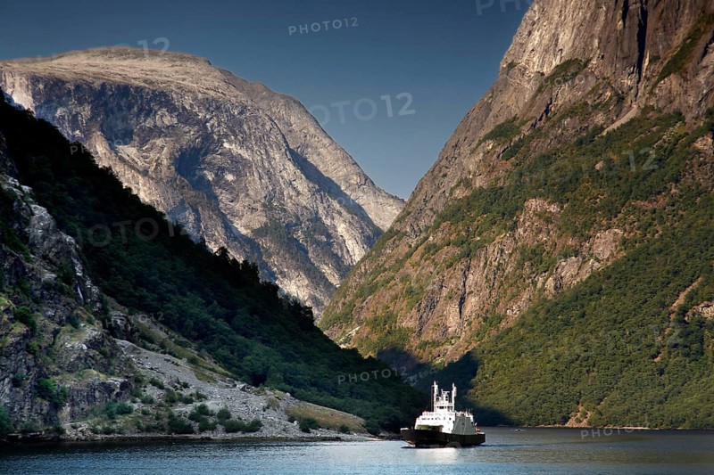 Ferry sails through the impressive Nærøyfjord near Gudvangen under steep mountain faces, Gudvangen, Norway