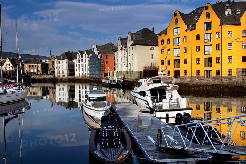 Colourful buildings and boats are reflected in the calm waters of Ålesund Harbour, Ålesund, Møre og Romsdal, Norway