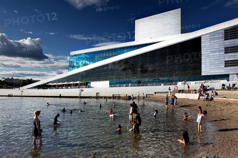 Modern opera next to beach, people enjoying sunny day in water, Oslo, Norway